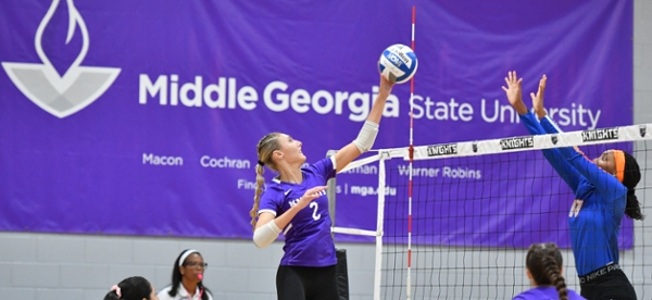 Knights volleyball player spiking the ball over the net during a game. 