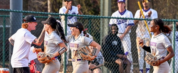 Knights softball players give Coach Wimpy high fives as they walk off of the field. 