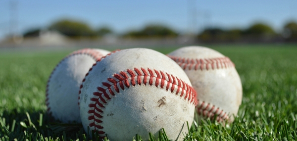 Baseballs sitting in a green, grassy baseball field. 