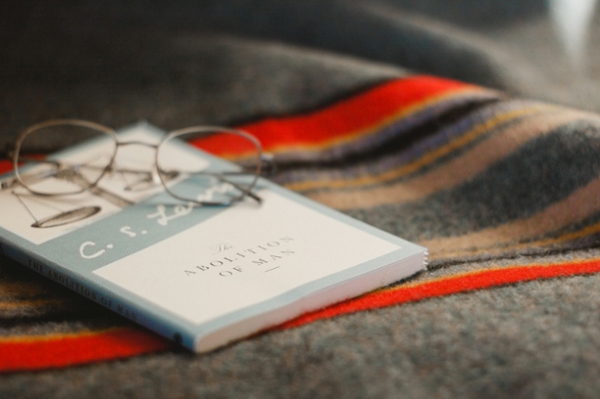 Grey framed eyeglasses sit on a closed book. 