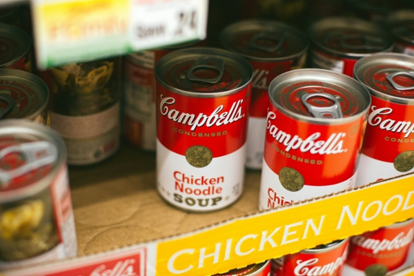 Cans of Campbell's chicken noodle soup sit on a shelf. 