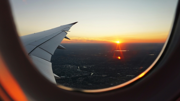 Photo of the wing of a plane with the sunset in the distance.