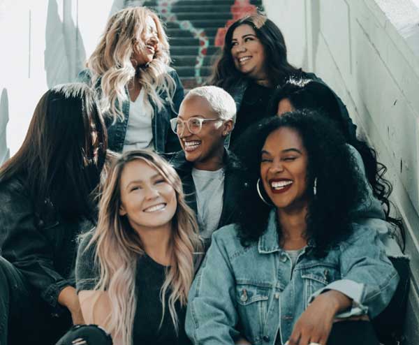 Group of diverse women laughing on a stoop. 