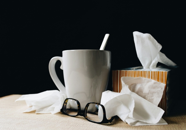 Glasses, tissues, and a mug sit on a desk.