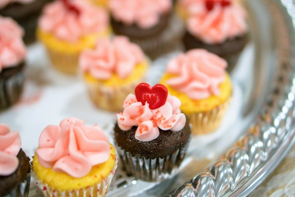 Cupcakes topped with red candy hearts. 