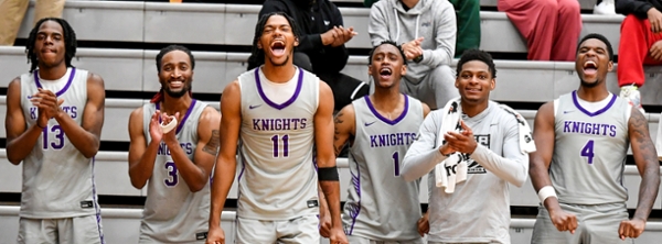 Knights men's basketball players cheering courtside.