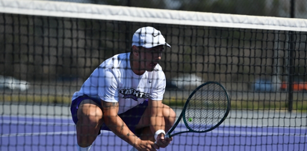 Men's tennis player rests on the court during a match.