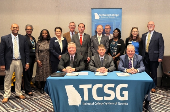 Shareholders sign the agreement at a table with a TCSG tablecloth.