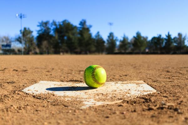 Softball rests on a diamond on a field. 