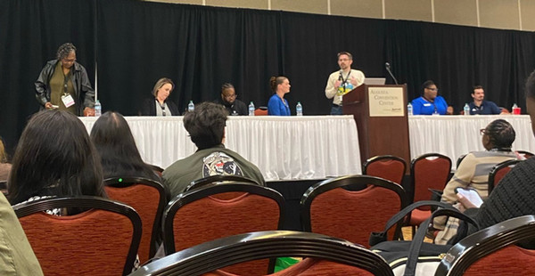 Carolyn Clark (far left) and Wesley Sewell (center at podium) as they presented on a panel for enrollment professionals
