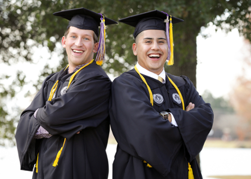 Two male graduates pose at an MGA commencement ceremony. 