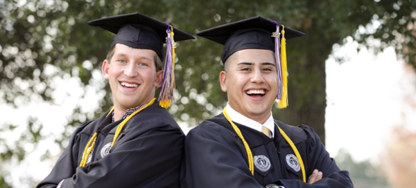 Two male graduates pose at an MGA commencement ceremony. 