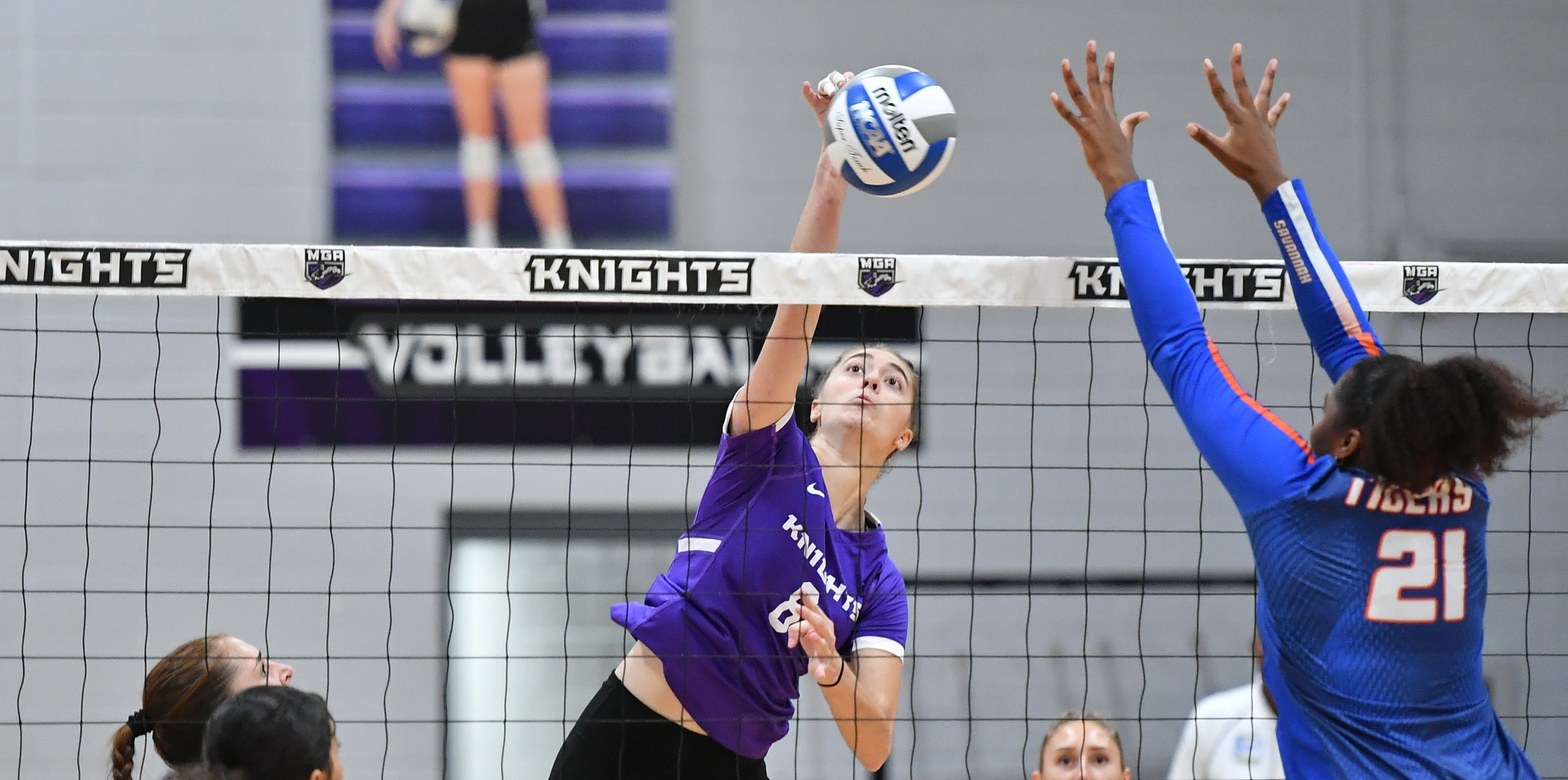 Knights volleyball player hits the ball over the net.
