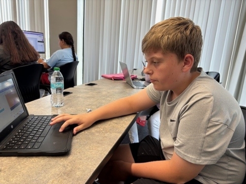 Students in elementary, middle, and high school engaged in coding exercises and games to collaborate at summer coding lab.