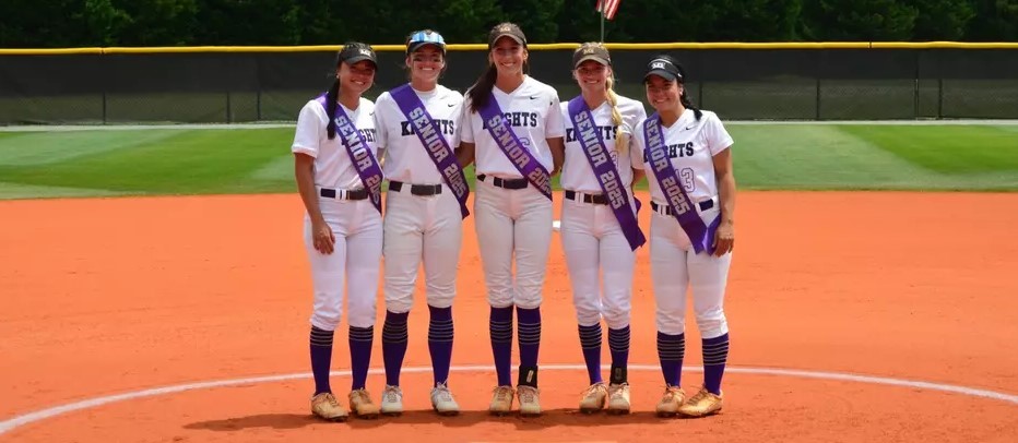 Senior Knights softball players pose on the mound.