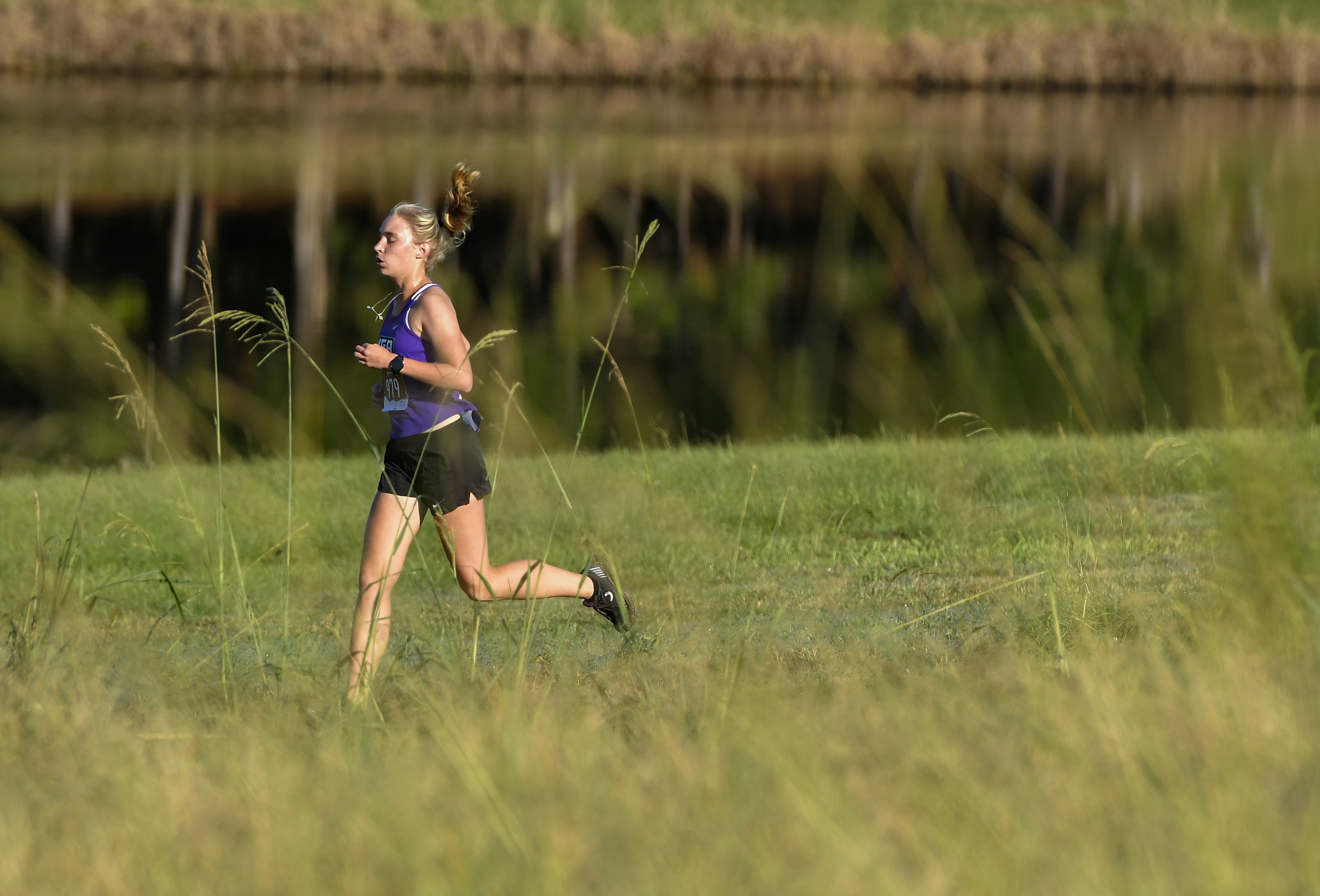 Knights omne's cross country runner jogs a course during golden hour.