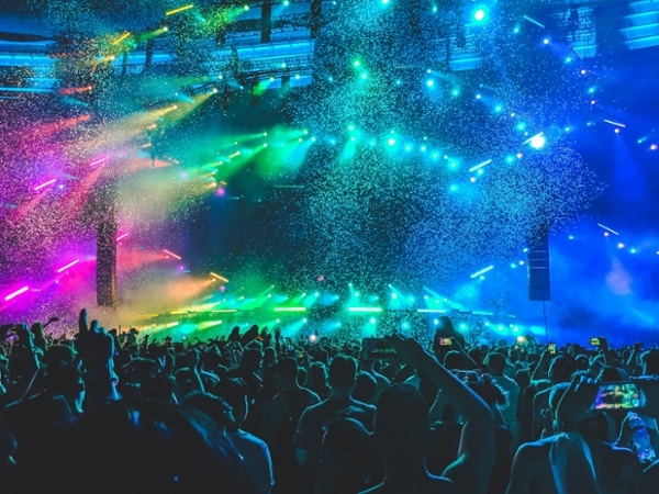 Crowd cheers at a concert as confetti falls. 