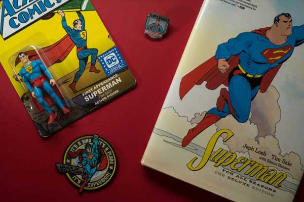 Superman comics and pins on a red table. 