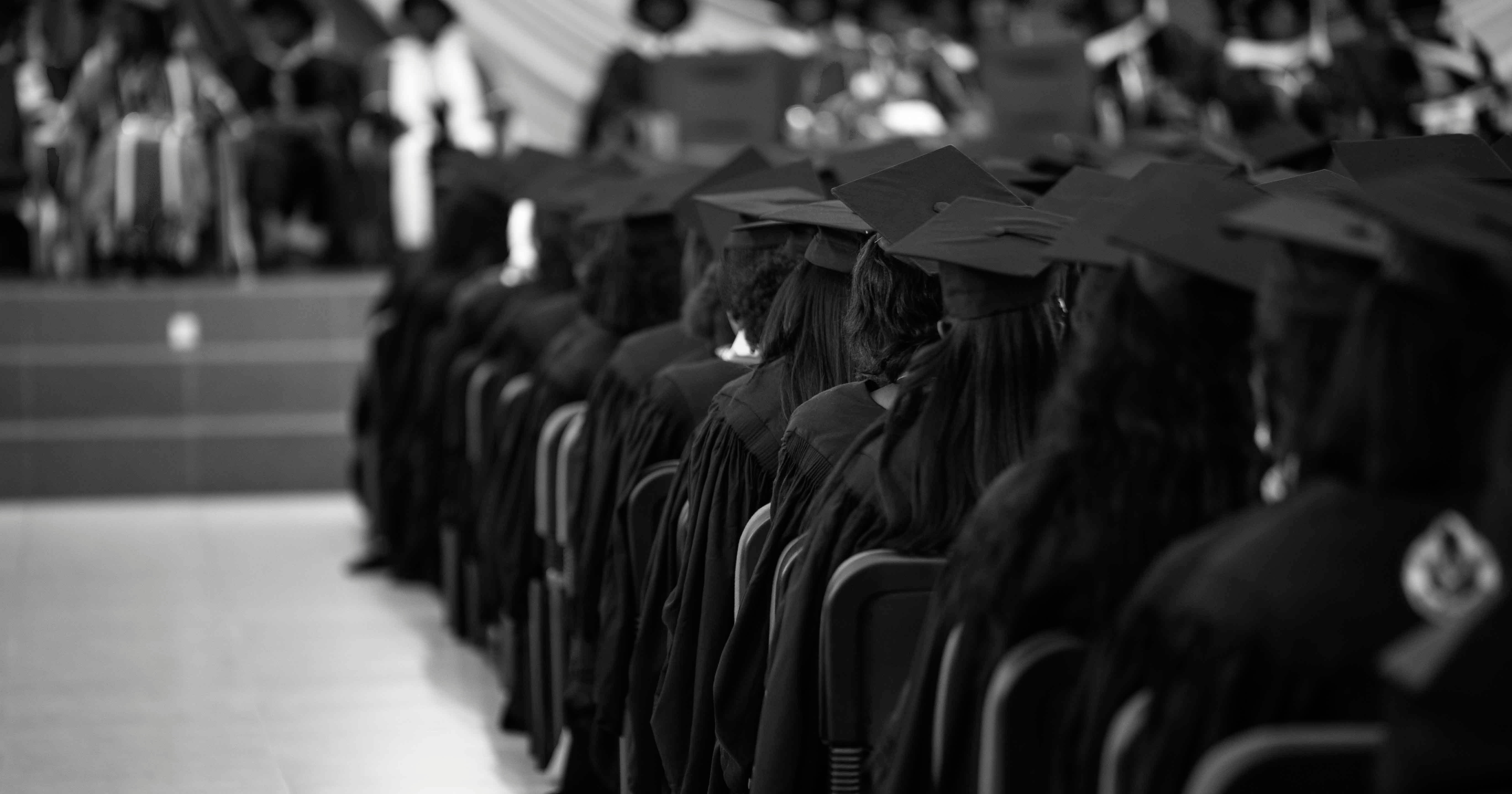 Graduates sitting in the crowd at a commencement ceremony. 