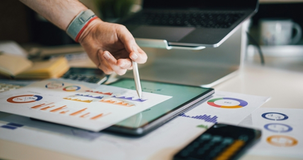 Person writes on a piece of paper displaying analytics.