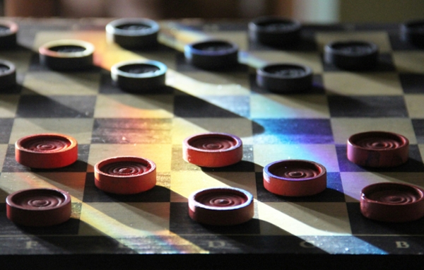 Black and red checkers pieces on a board. 