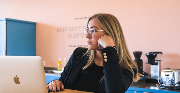 Woman works on a laptop at a desk.