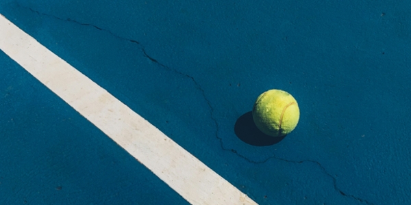 Tennis ball rests on a blue court. 