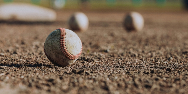 Baseballs sitting in dirt.