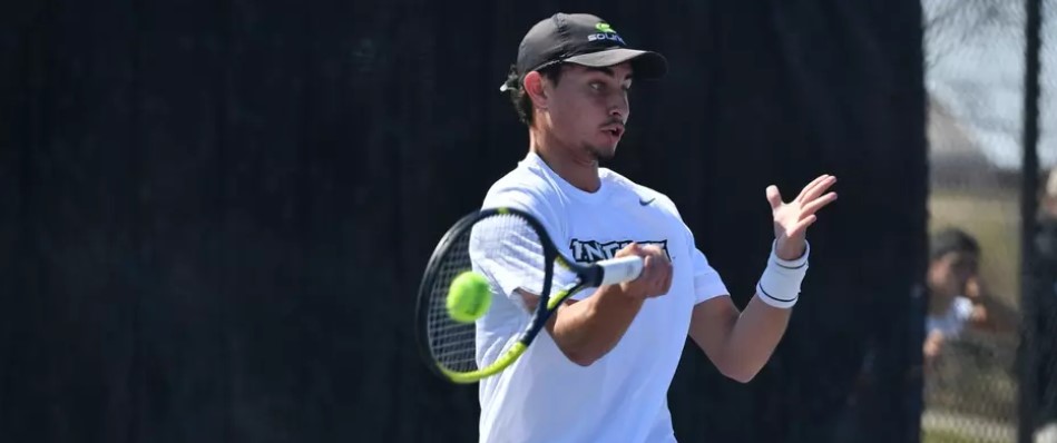 Knights men's tennis player hits the ball during a match. 