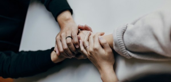 Two people hold hands across a table. 