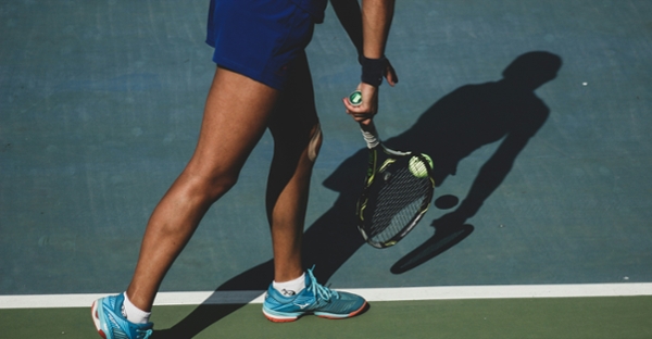 Tennis player sands on a court.