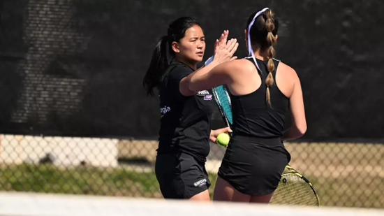 Knights women's tennis players high five.