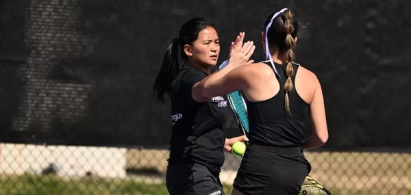 Knights women's tennis players high five.