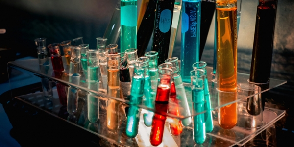 Chemistry tubes and beakers filled with colorful liquids in a lab. 