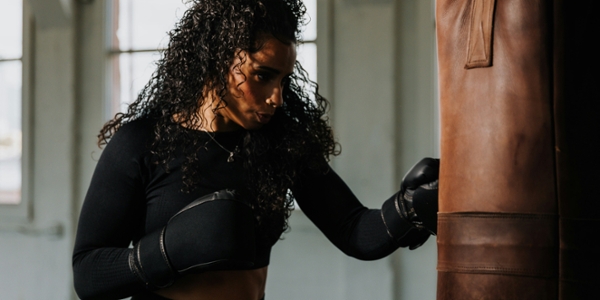 Woman wearing boxing gloves hitting a punching bag. 