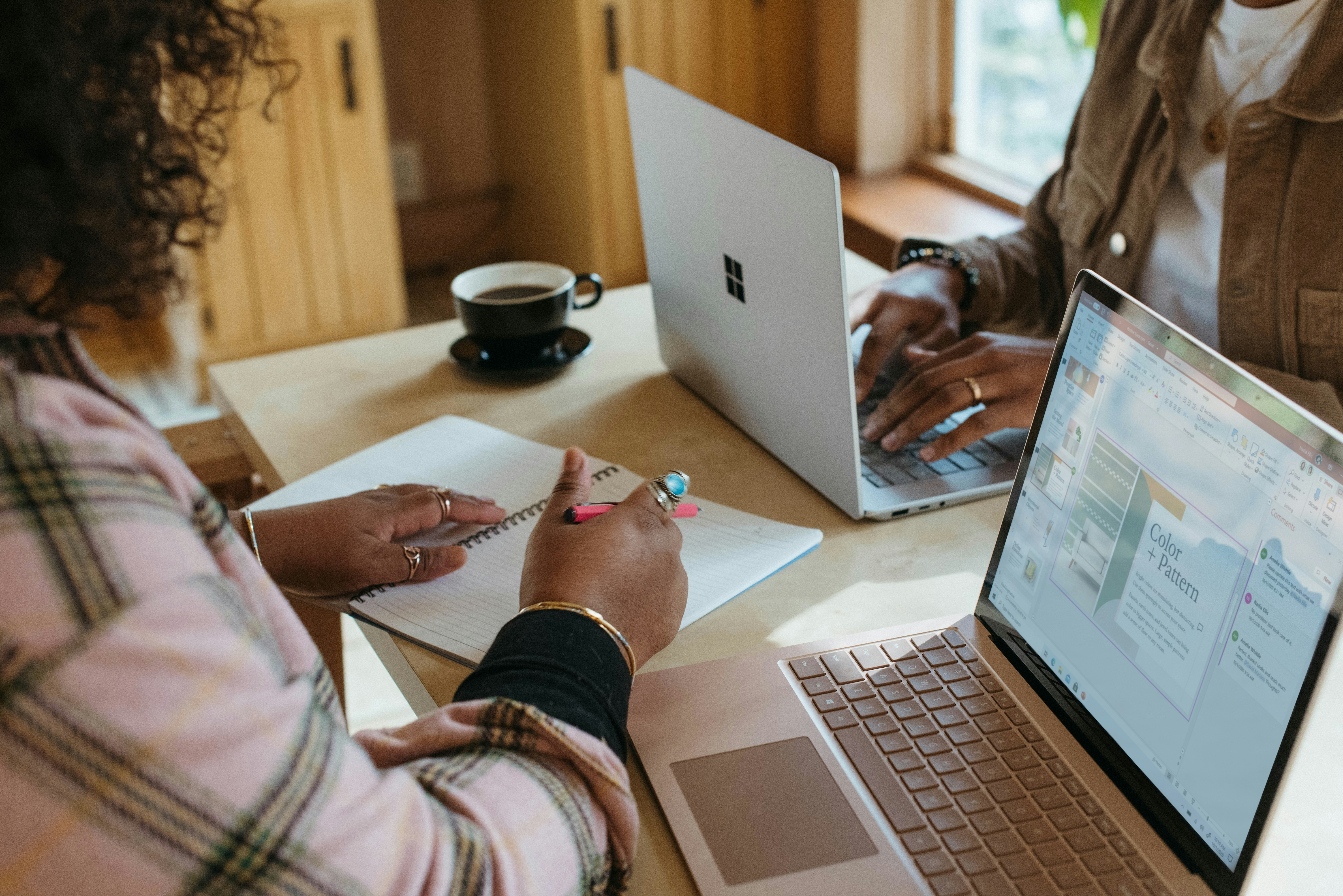 Close up of two women talking over laptops.
