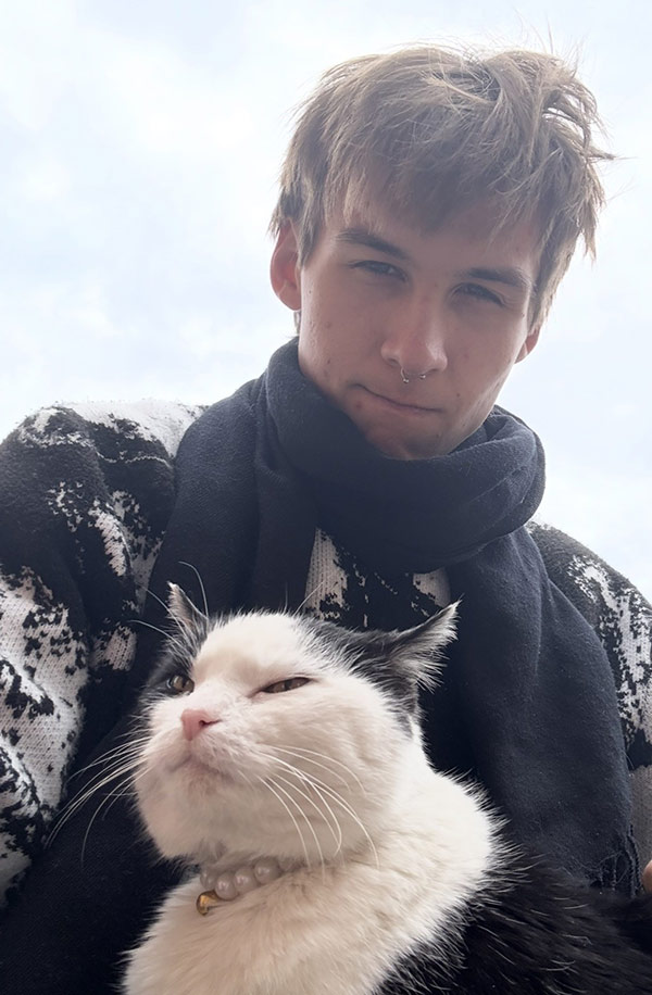 Image of MGA student Christopher Cook posing with his cat.