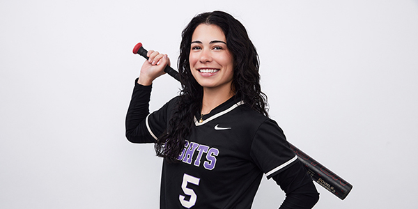 MGA student, Madison Cosgrove, posing during media day photos for softball holding up a bat.