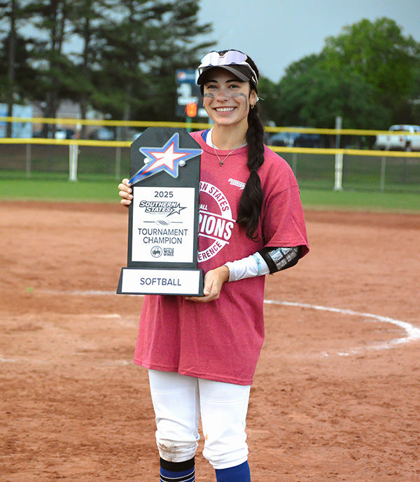 MGA student, Miranda Cosgrove, posing with a trophy reading, "2025 Softball Tournament Champion."