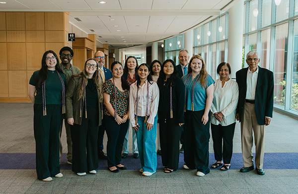 A group photo of MGA study abroad attendees and faculty standing in a sunlit campus building.