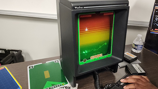 A Vectrex tabletop arcade console displaying a green and yellow retro game screen on a table.