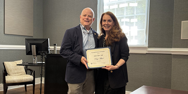 Paige Alford stands with Dr. Will Evans, Dean of the GCSU College of Health Sciences, holding her Hall of Fame induction certificate.