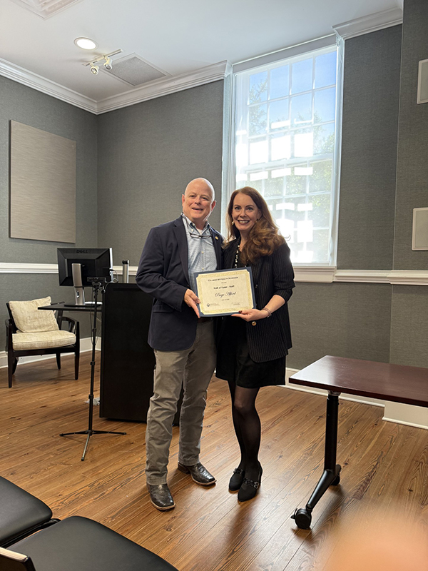 Paige Alford stands with Dr. Will Evans, Dean of the GCSU College of Health Sciences, holding her Hall of Fame induction certificate.