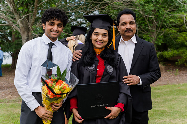 MGA Spring 2026 graduate posing outside with family.