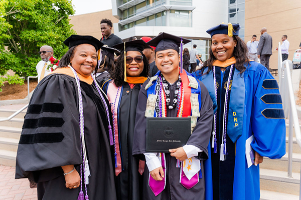 MGA Spring 2026 graduates posing outside with faculty.